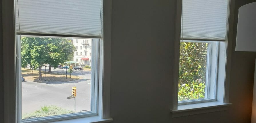Windows in a living room that look out to the street on a sunny day