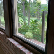 An image of a Climate Seal window insert is virtually invisible next to the brick exterior of the home