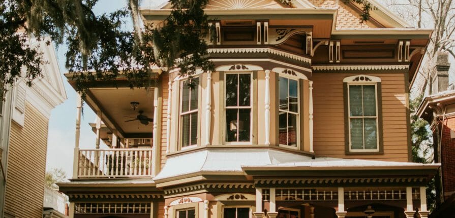 A close-up image of an old, Victorian-style home, warn sunshine spills across it